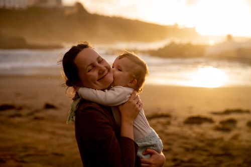 Free A joyful mother and child bonding moment captured on a beach at sunset. Stock Photo