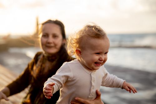 Free A happy mother and baby enjoying a sunny day by the sea, capturing their bond. Stock Photo