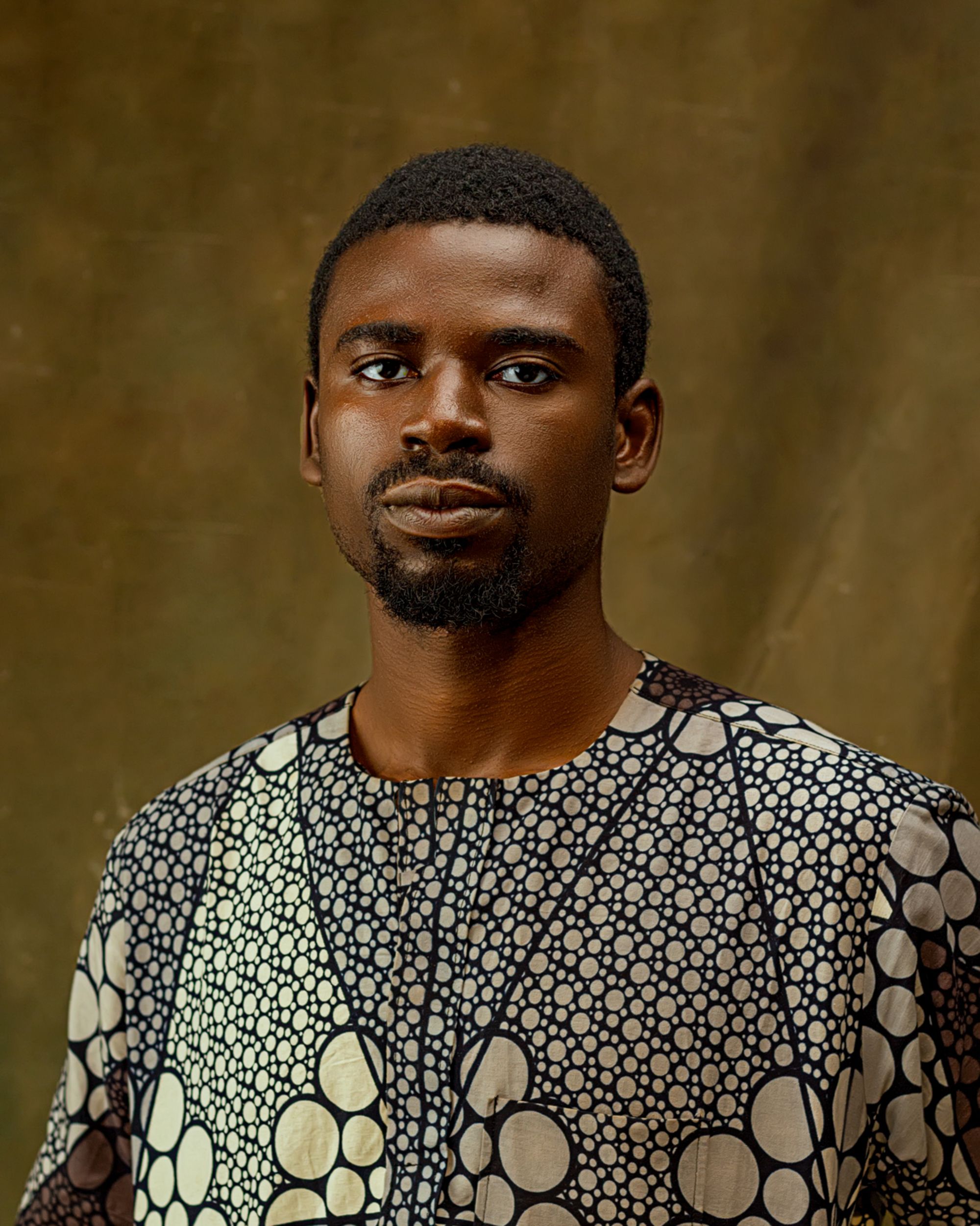 A captivating portrait of a man wearing a geometric patterned shirt, showcasing modern fashion and African style.