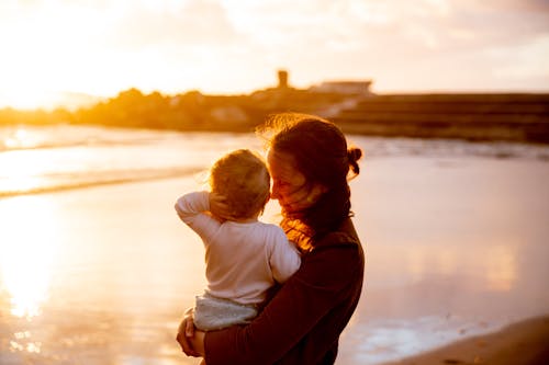Woman Carrying Baby in White Shirt Watching the Sunset