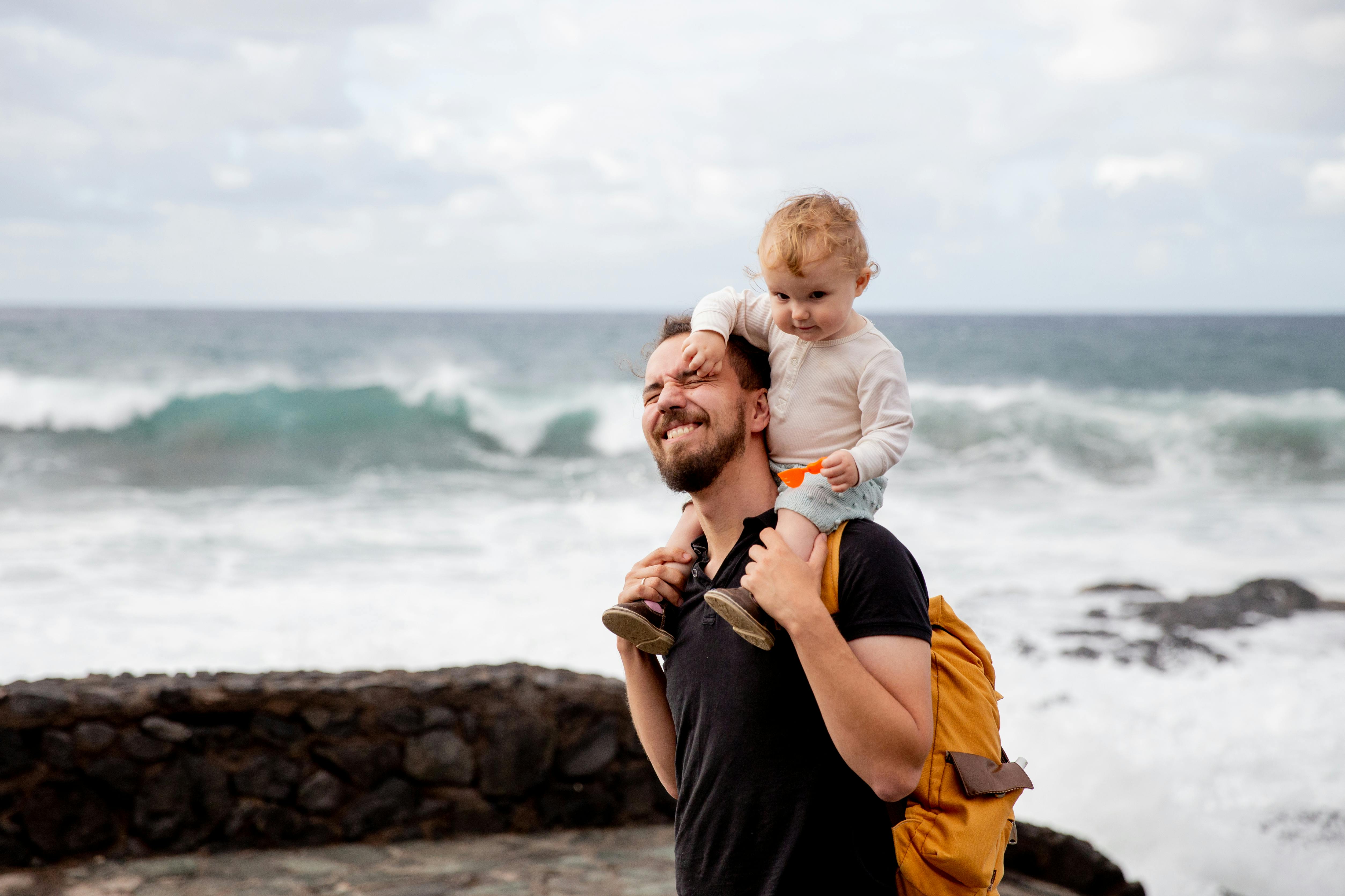 man in black shirt carrying little kid on his shoulder