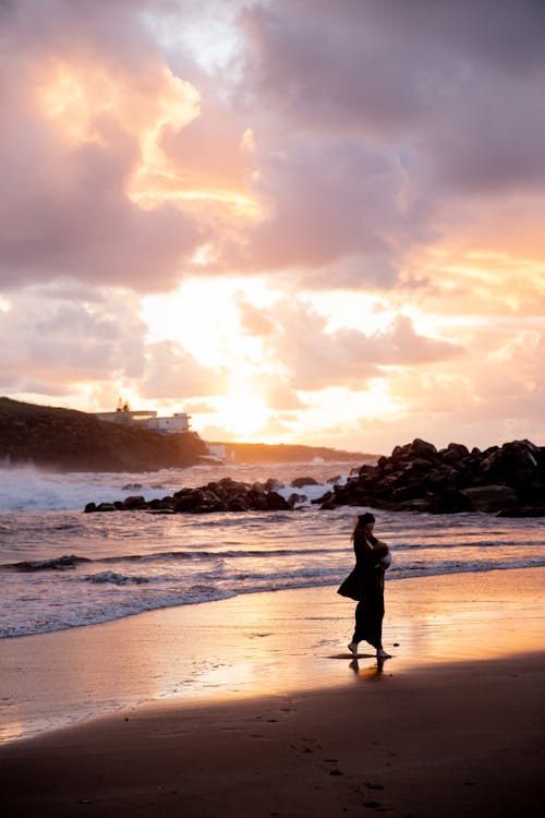 Free Silhouette of Woman Walking on Beach during Sunset Stock Photo