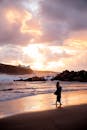 夕阳西下，天空绚烂，一名女子的剪影走在海滩上