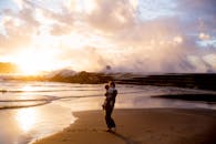 日落时分，母亲抱着孩子在海边的温馨场景