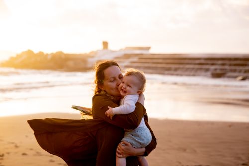 Free A mother lovingly embraces her child on a picturesque beach during sunset. Stock Photo