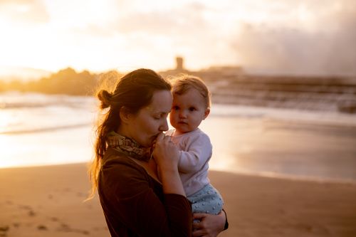 Free Heartwarming moment between mother and child on a serene beach at sunset. Stock Photo