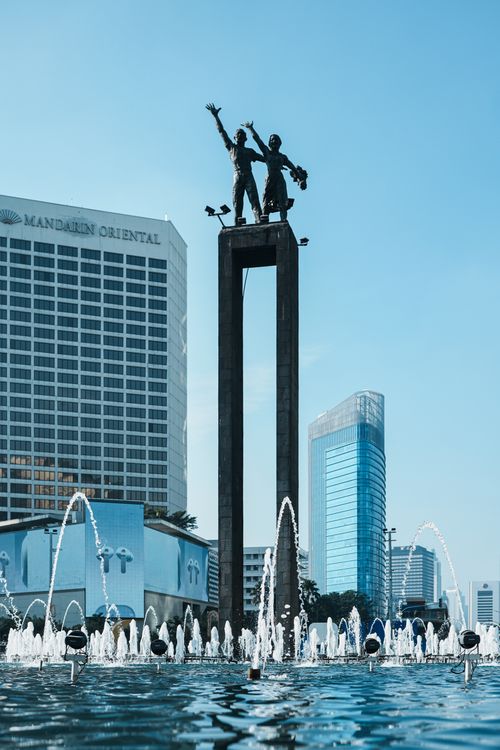 Free View of the iconic Selamat Datang Monument with fountains in Jakarta, Indonesia, under a clear blue sky. Stock Photo