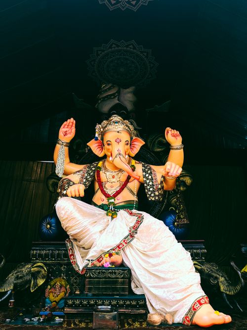 Free Vibrant statue of Lord Ganesha adorned with ornaments in a dimly lit temple setting. Stock Photo