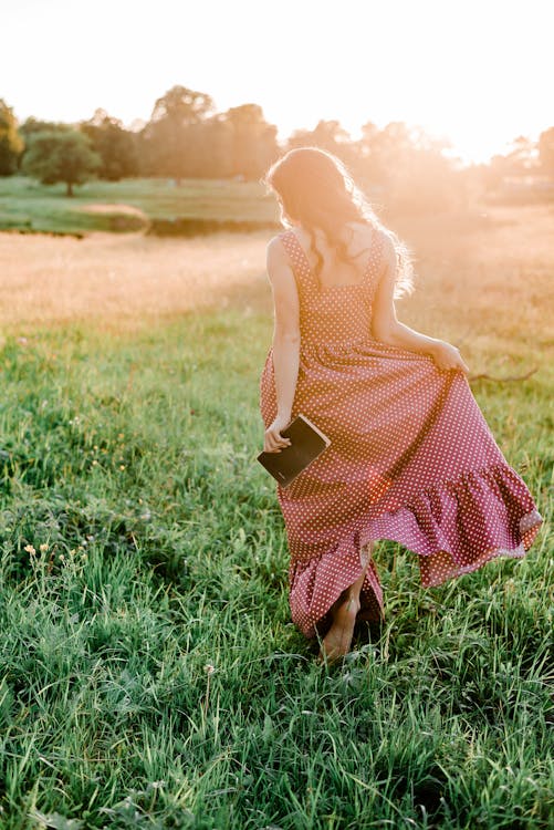 Woman in Polka Dot Dress Standing on Green Grass Field