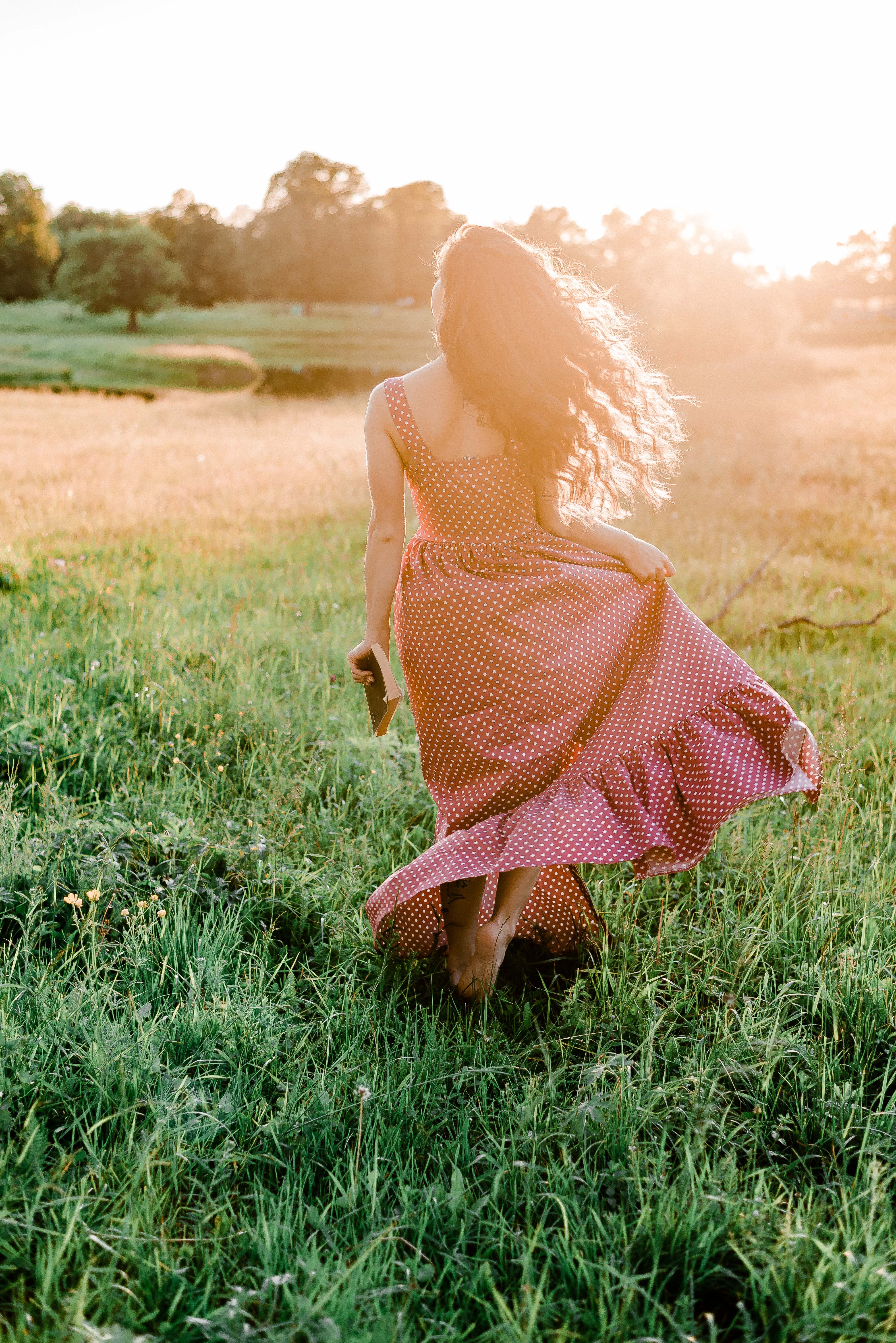 Woman in Polka Dot Dress Walking on Green Grass Field · Free Stock Photo