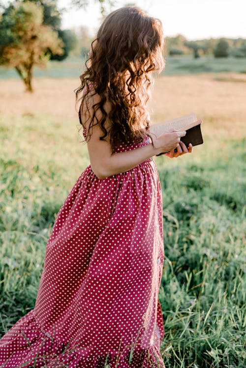 Chica En Vestido De Lunares Rojos Y Blancos Sosteniendo Libro