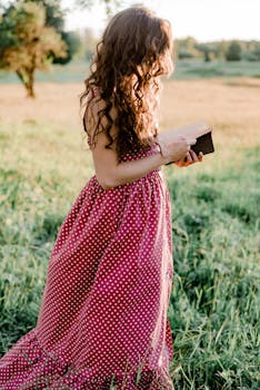 一位穿着圆点连衣裙的女子在阳光明媚的乡村田野里看书