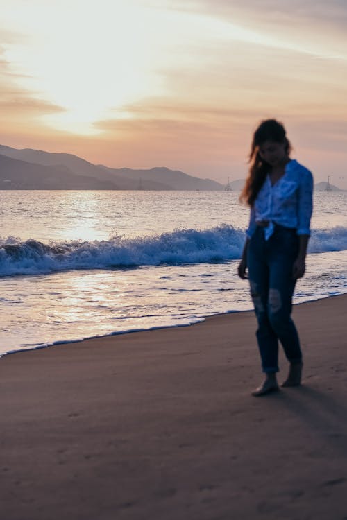 Woman Standing on Seashore During Sunset