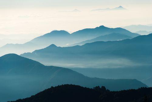 Free Beautiful layers of a misty mountain range in soft blue tones under a tranquil sky. Stock Photo