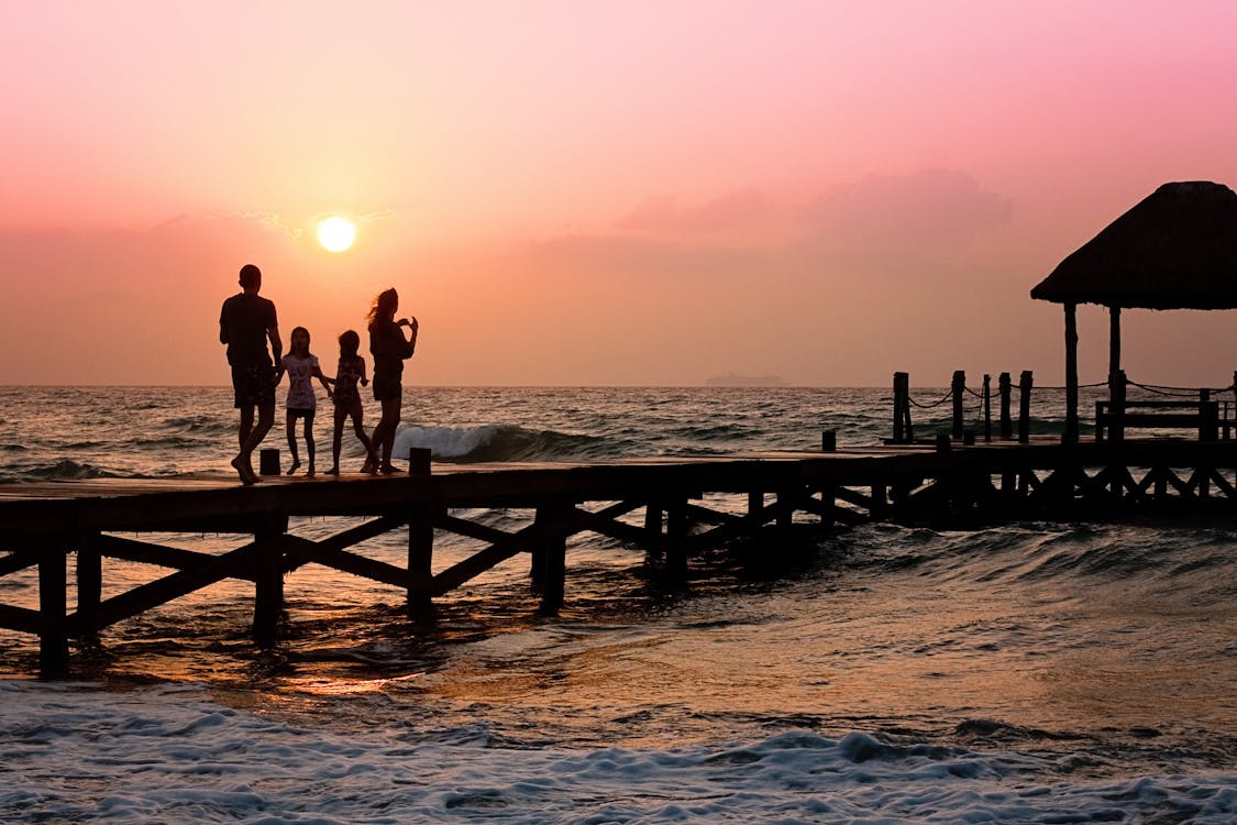 Free People Standing on Dock during Sunrise Stock Photo