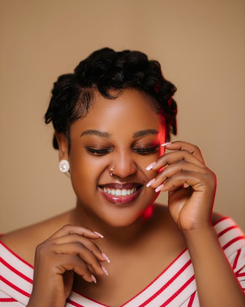 Free Portrait of a joyful woman with short hair, wearing earrings, and a striped top, smiling warmly. Stock Photo