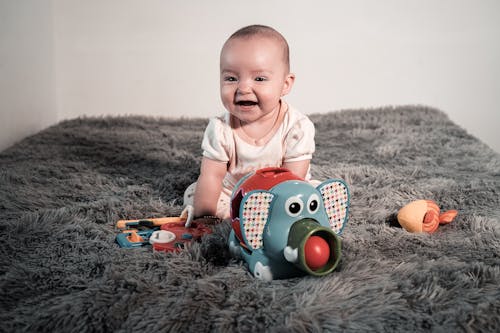 Free Baby Sitting on Fur Carpet Playing with Toys Stock Photo
