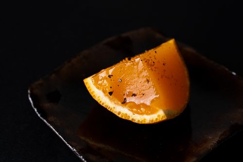 Free A sophisticated piece of yuzu jelly elegantly presented on a dark ceramic plate, embodying Japanese culinary art. Stock Photo