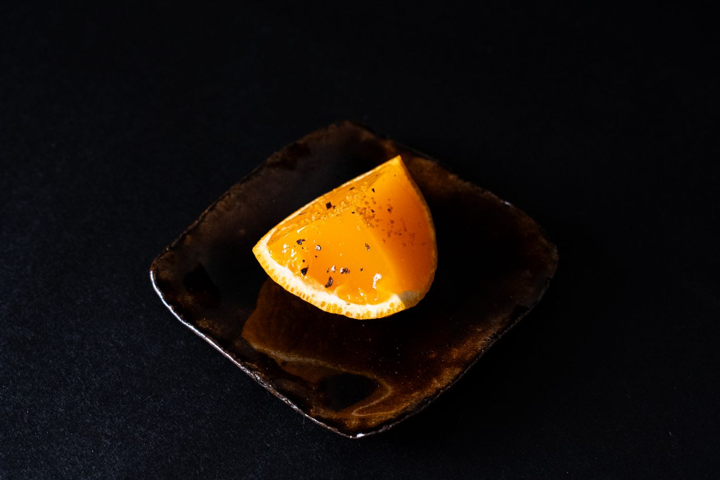 Spicchio d'arancia su un piatto di ceramica scura