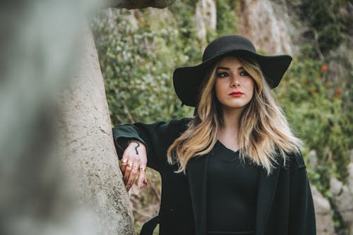 Free Woman in Black Long Sleeve Shirt and Black Hat Standing Beside Tree Stock Photo