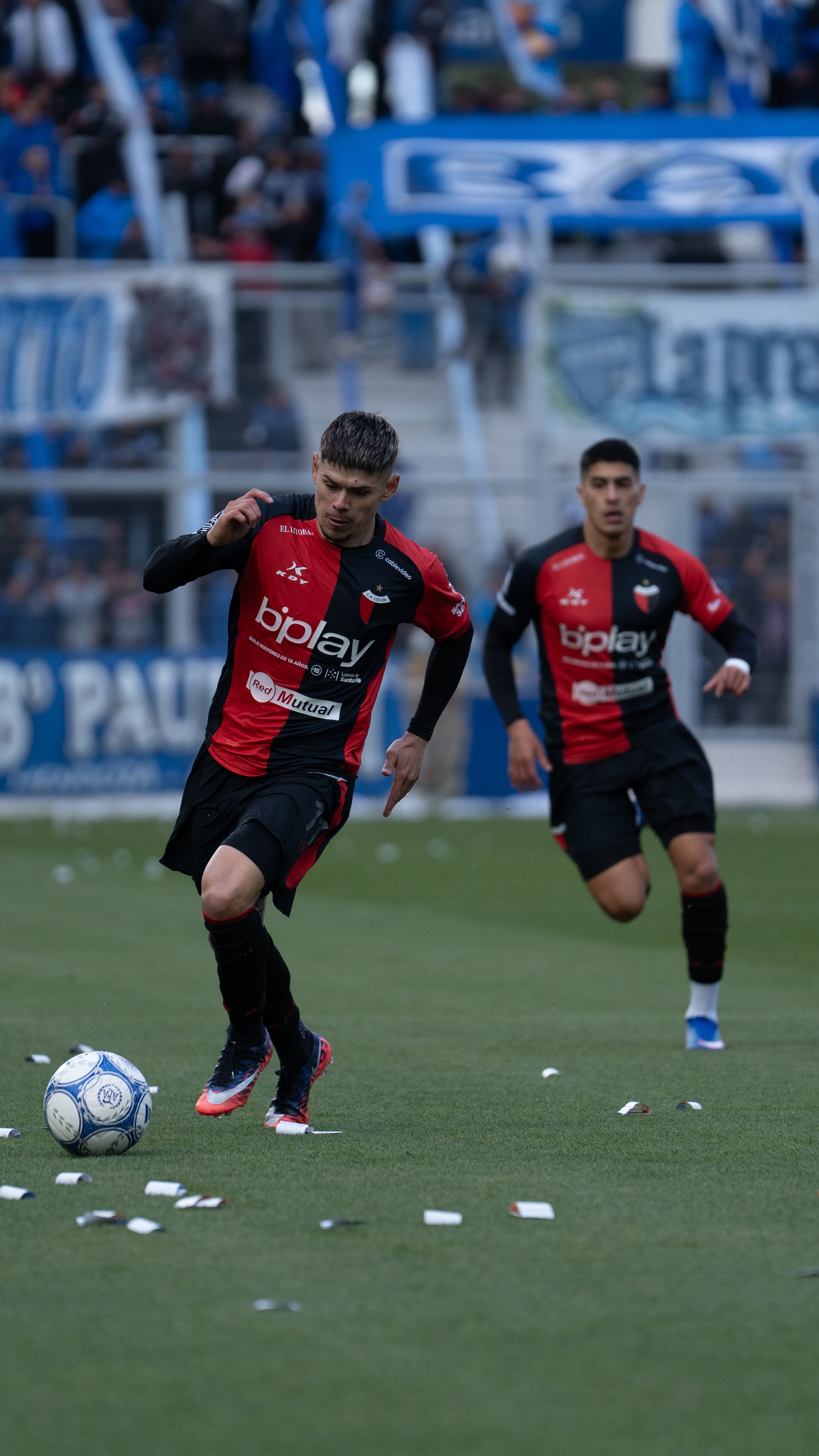 Dynamic action shot of soccer players in a professional match with crowd in the background.