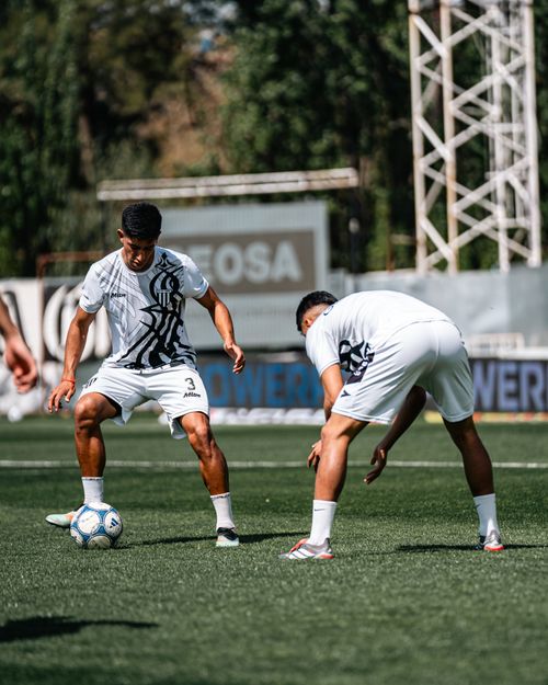 Free Two men in sports uniforms practicing soccer on a sunny outdoor field. Stock Photo