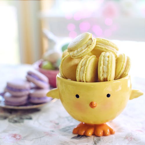 Yellow Ceramic Chick Bowl With Yellow Macarons on White and Pink Floral Table Cloth