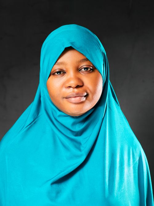 Free A calm portrait of a woman clad in a vibrant blue hijab with a dark backdrop. Stock Photo