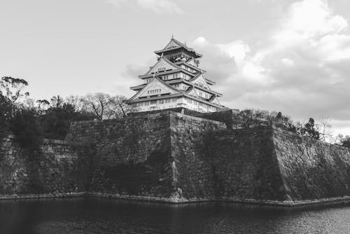 Grayscale Photo of Osaka Castle Near Body of Water