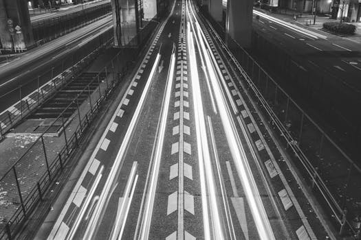 Black and white long exposure capture of light streaks on a road in Osaka, Japan at night.