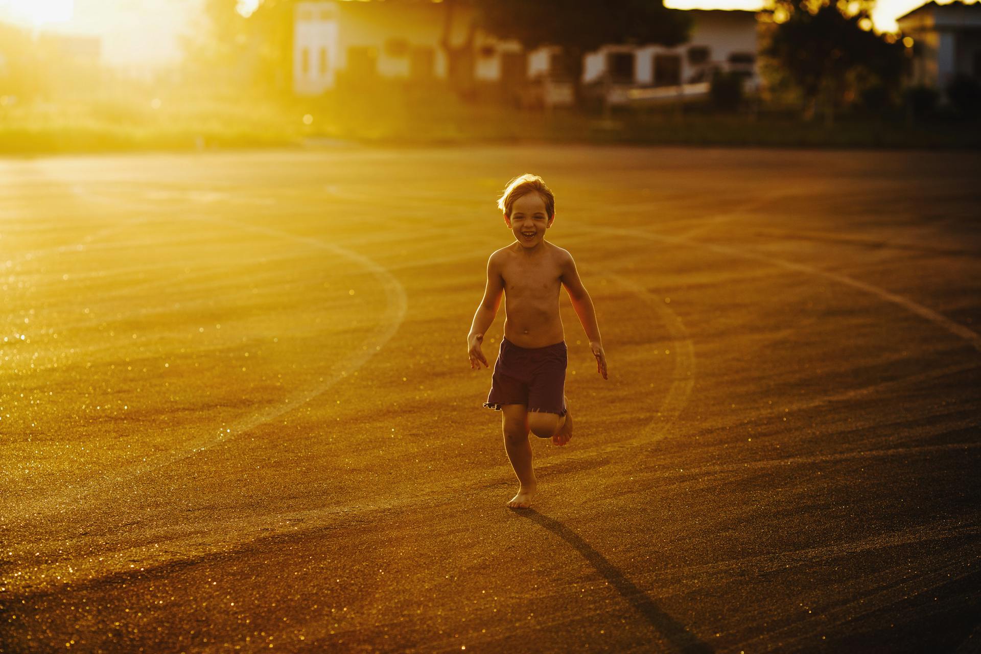 A happy child runs barefoot on a sunny day, enjoying the freedom of an open field at sunset.