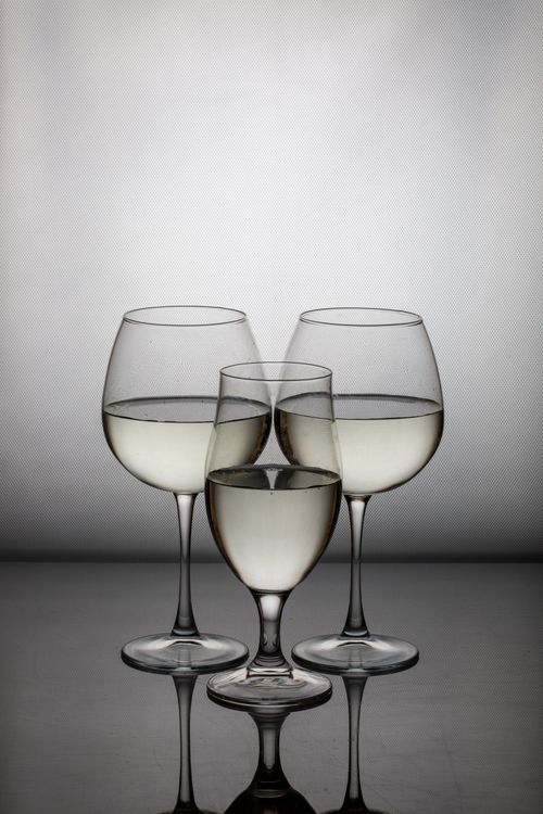 Free Trio of wine glasses with reflections creating a symmetrical and artistic composition. Stock Photo