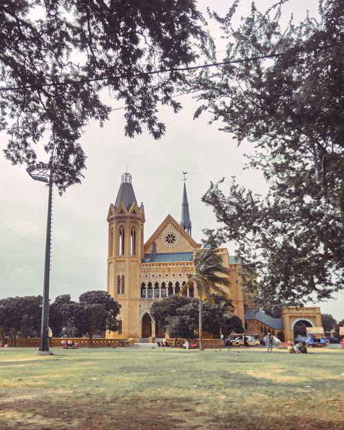 Free A captivating view of the historic Frere Hall in Karachi, framed by lush trees on a bright day. Stock Photo
