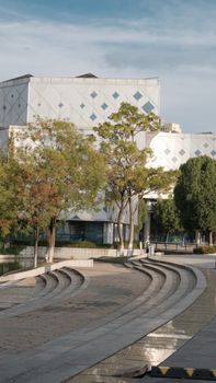 A contemporary architectural structure surrounded by trees and curved walkways, captured on a bright day.