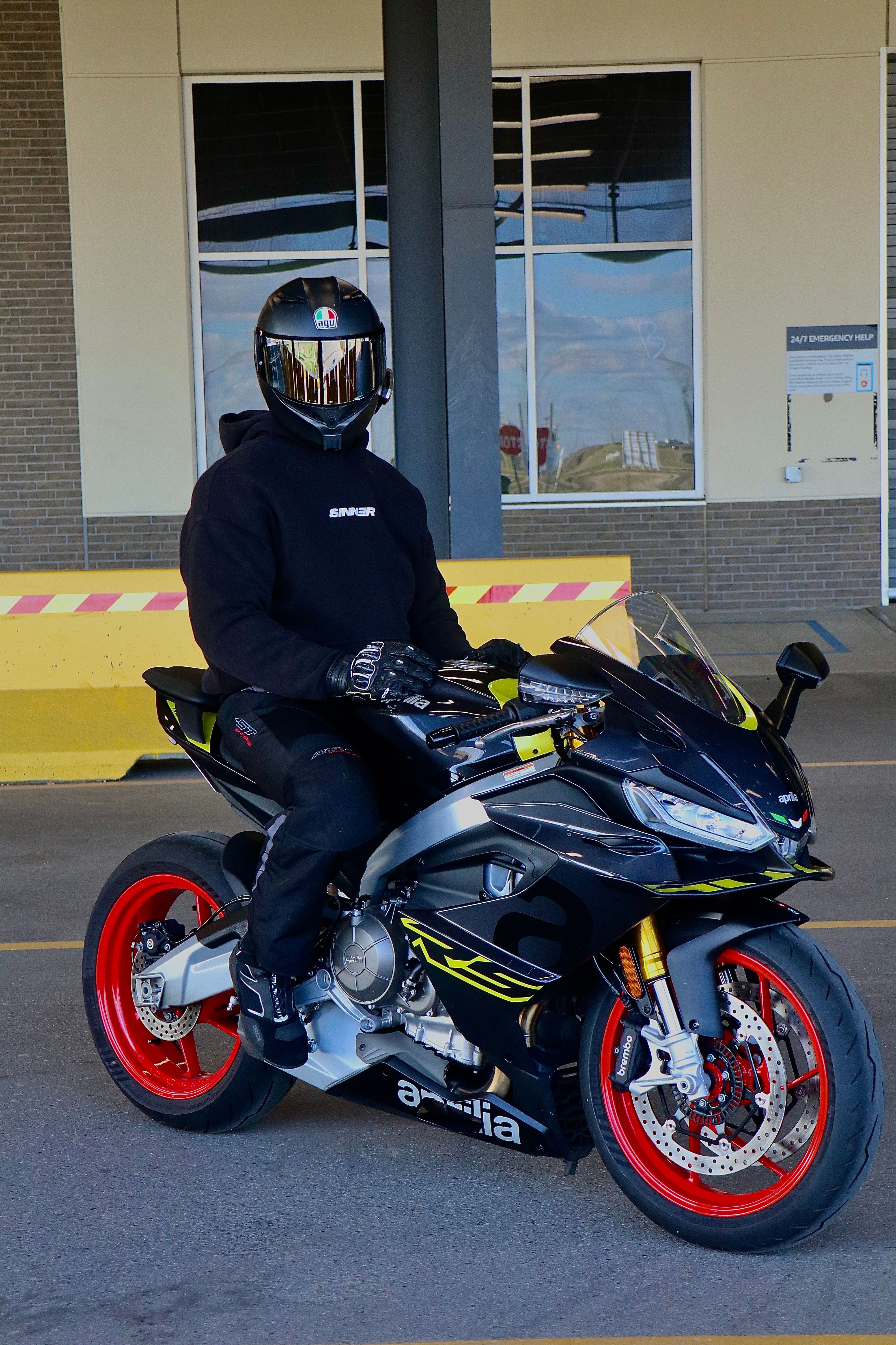 A motorcyclist wearing full protective gear sits on a sleek sport bike outdoors.