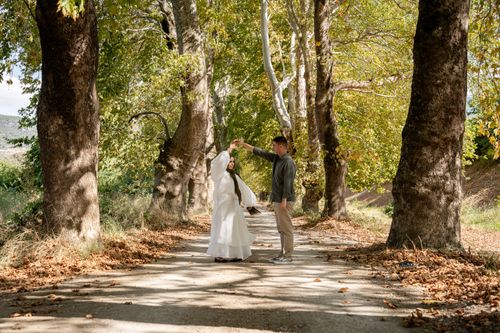 Free A couple dancing under the trees on a sunlit, leaf-covered path in autumn. Stock Photo