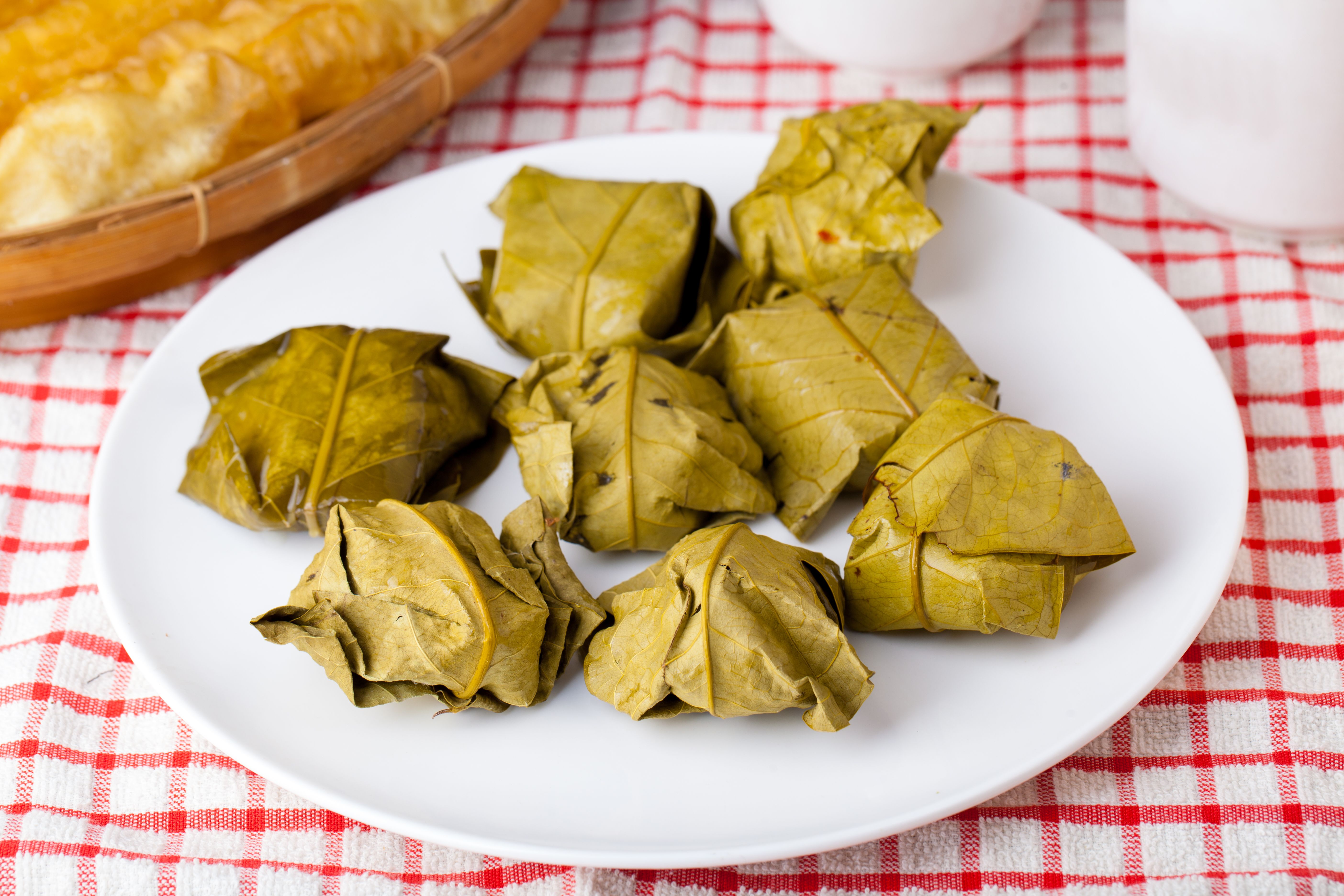 Traditional Indonesian Tape Ketan wrapped in banana leaves served on a white plate.