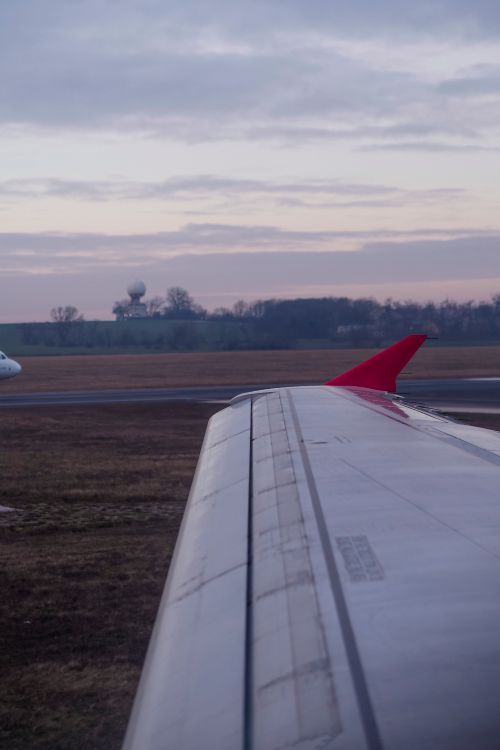 Free Airplane wing with red tip at twilight on tarmac, serene landscape view. Stock Photo