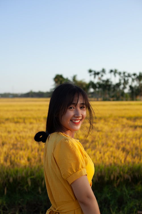 Woman in Yellow Dress Standing on Green Grass Field