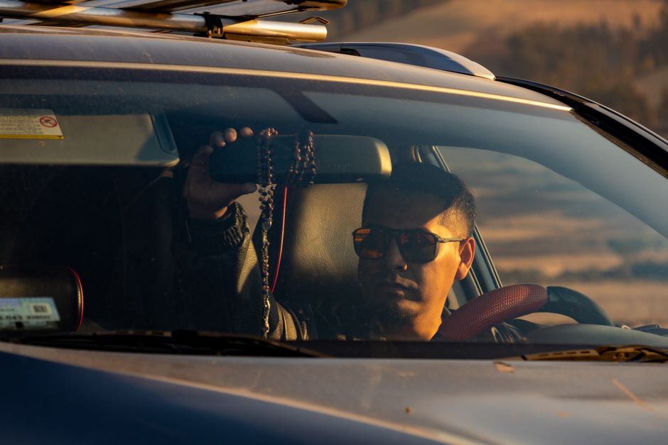 Driver wearing sunglasses in a car at sunset
