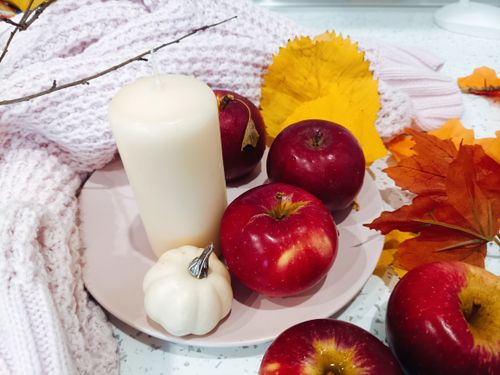 Free A warm autumn arrangement with apples, leaves, and a candle, evoking cozy fall vibes. Stock Photo