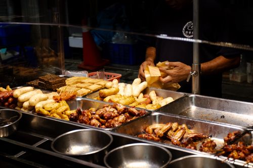 Free A bustling street food vendor selling a variety of grilled meats and snacks at a night market. Stock Photo