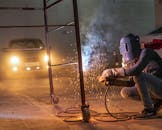 夜间，一名焊工在工业环境中工作，火花四溅