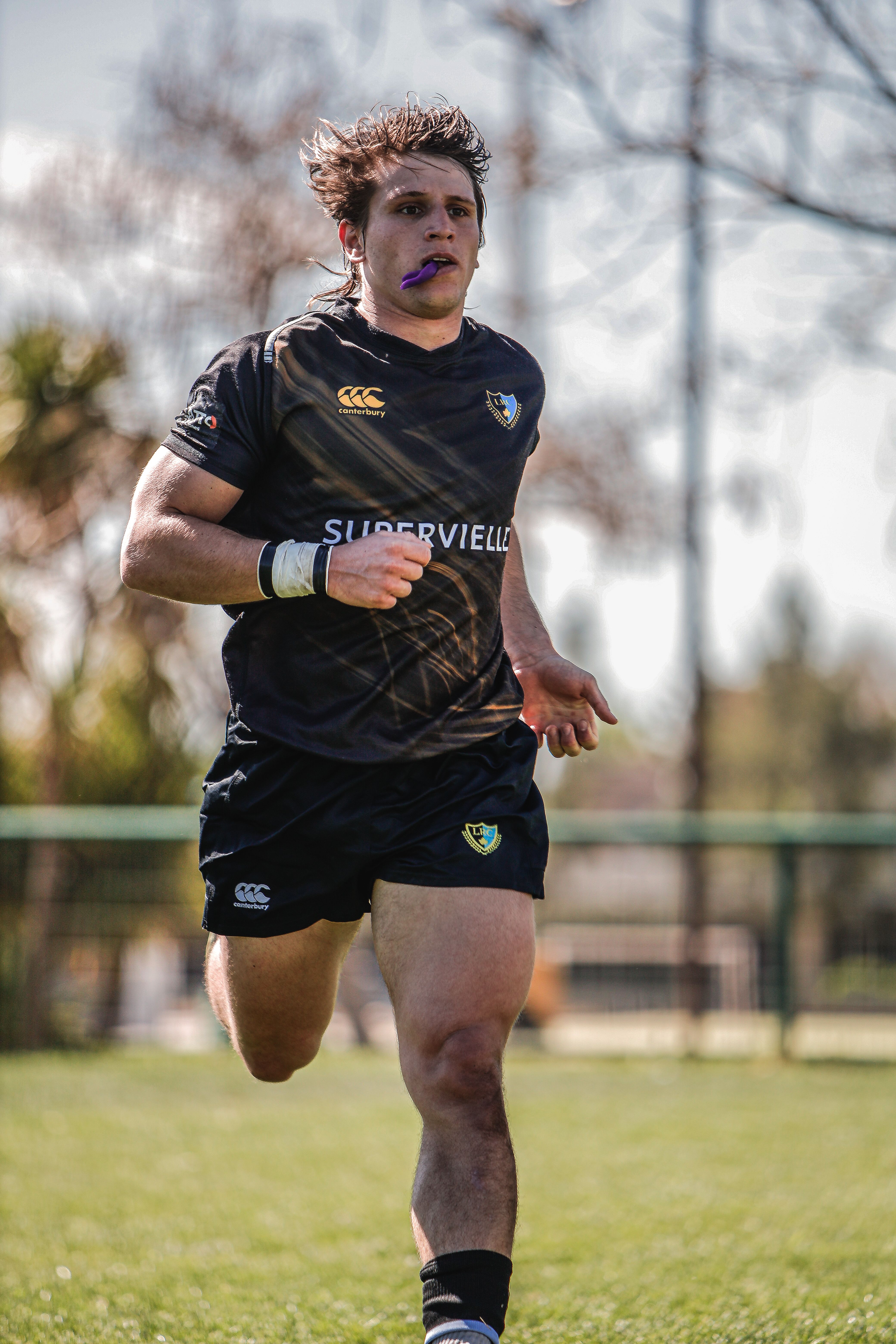 Focused rugby athlete running on a sunny day, showcasing determination and strength.