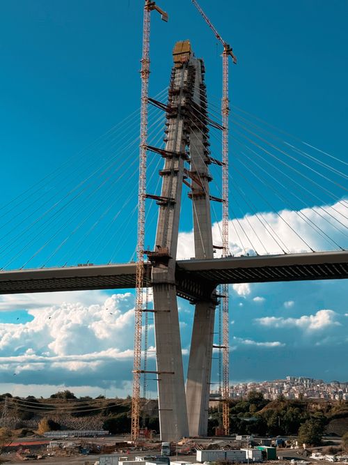 Free A stunning photo capturing bridge construction with cranes against a bright blue sky backdrop. Stock Photo