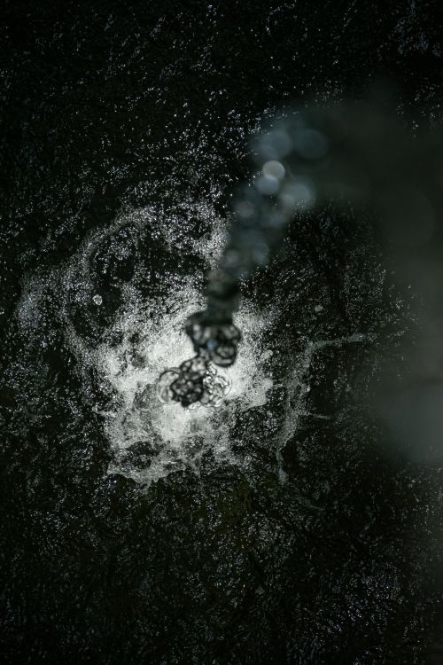 Free A mesmerizing shot of water splashing with a dark, textured background. Stock Photo