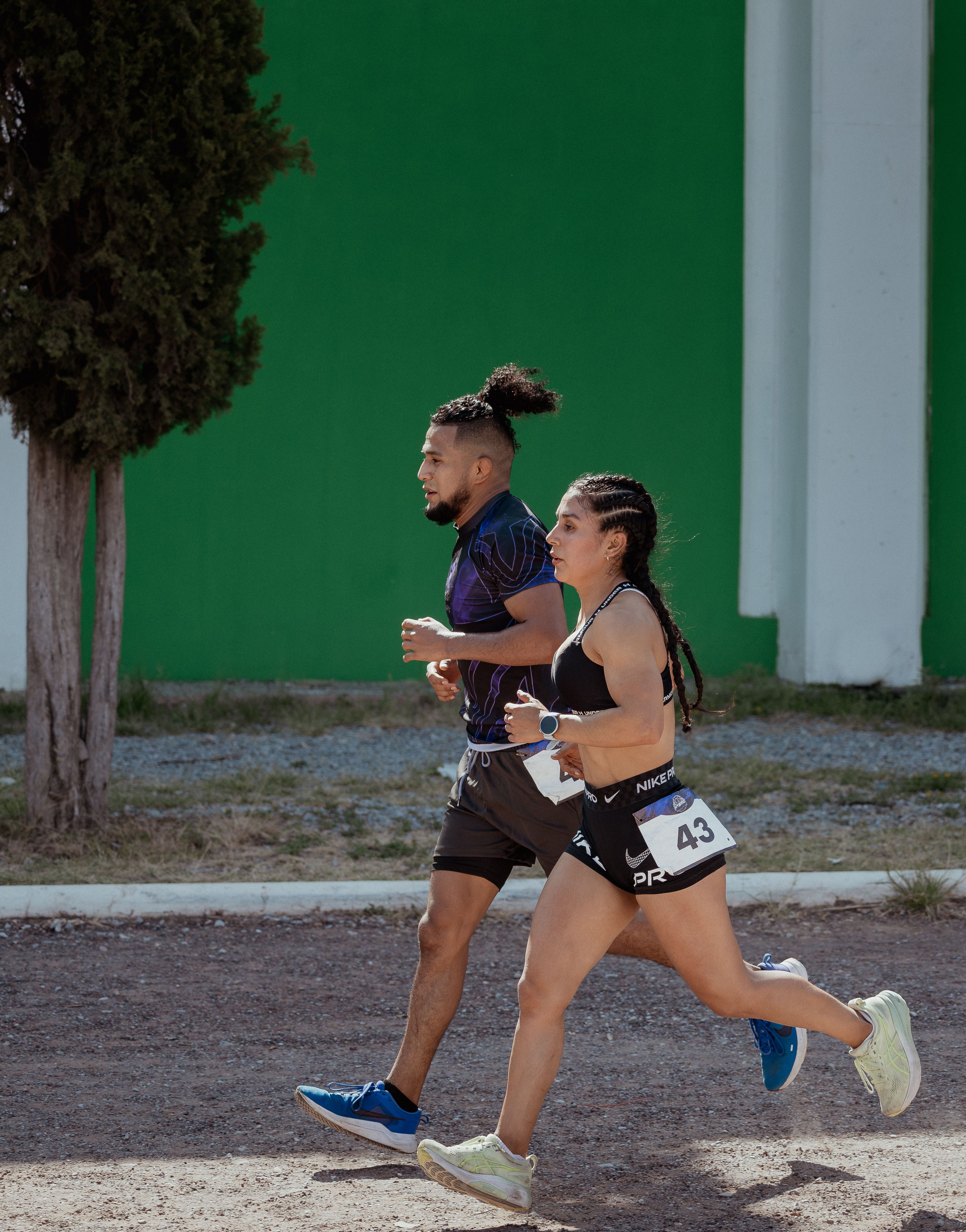 Two athletes racing outdoors on a sunny day in San Luis Potosí, showcasing endurance and teamwork in competitive trail running.