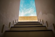 楼梯向上延伸，通向清澈的蓝天，象征着新的开始