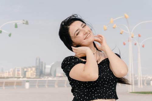 Free A cheerful woman enjoying a sunny day with the skyline of Baku, Azerbaijan in the background. Stock Photo