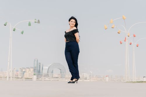 Free Woman standing outdoors in Baku with modern architecture and colorful street lamps. Stock Photo